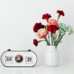 Alarm clock and vase of flowers on a table