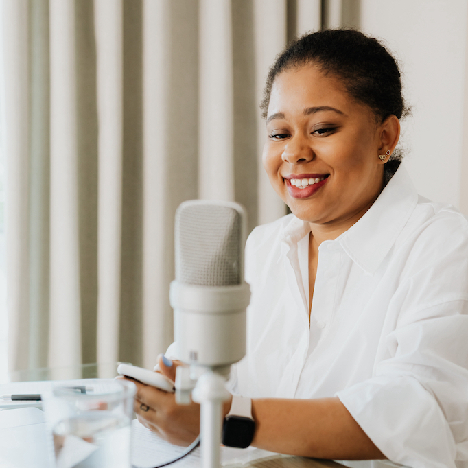 Image of a young black woman sitting in front of a microphone