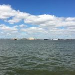Image of blue skies and clouds over water in New York Harbor, photography by R. Isip