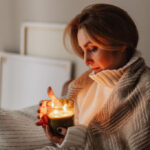 Woman wrapped in a blanket holding a lit candle in her hands