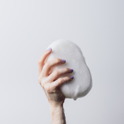 Woman holding a soapy sponge in her hand