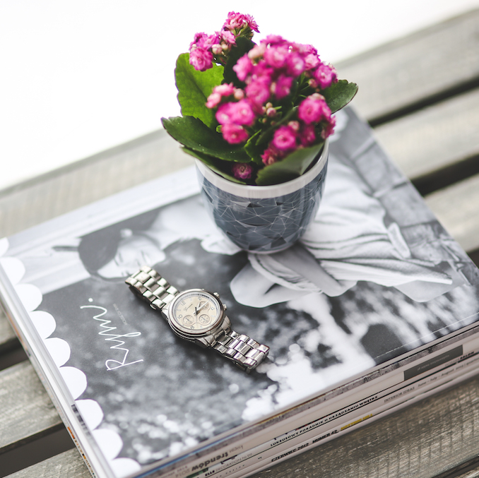 Stack of magazines with watch and flowerpot