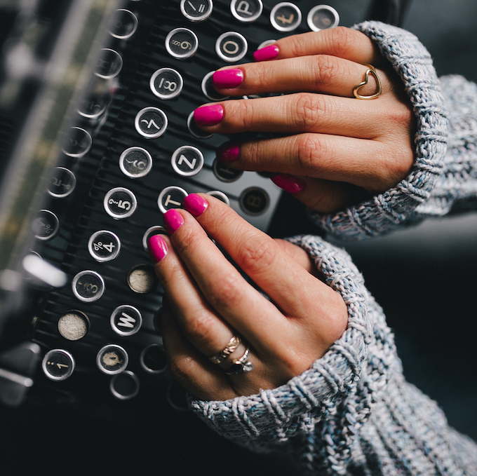 Close up of a woman typing on a typewriter