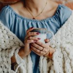 Woman wearing a blanket and holding a mug