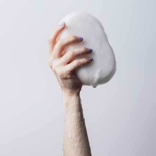 Woman holding a soapy sponge in one hand