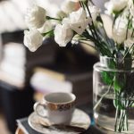 Close up of a vase of flowers and a teacup and saucer