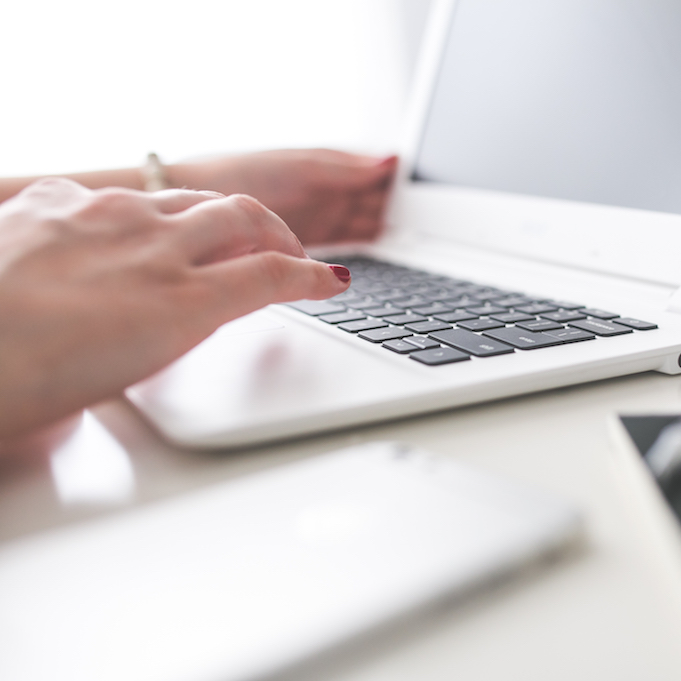 Woman typing on a white laptop