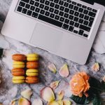Laptop with macarons and flowers on a table