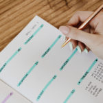 Woman holding a pen while using a paper planner