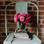 Flowers in a glass sitting on a stack of books on a chair