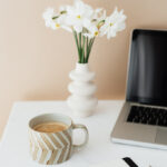 Mug, flowers, and a laptop on a desk