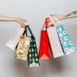 Two hands holding holiday gift bags