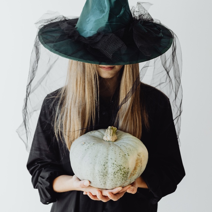 Woman dressed as a witch and holding a pumpkin in her hands

