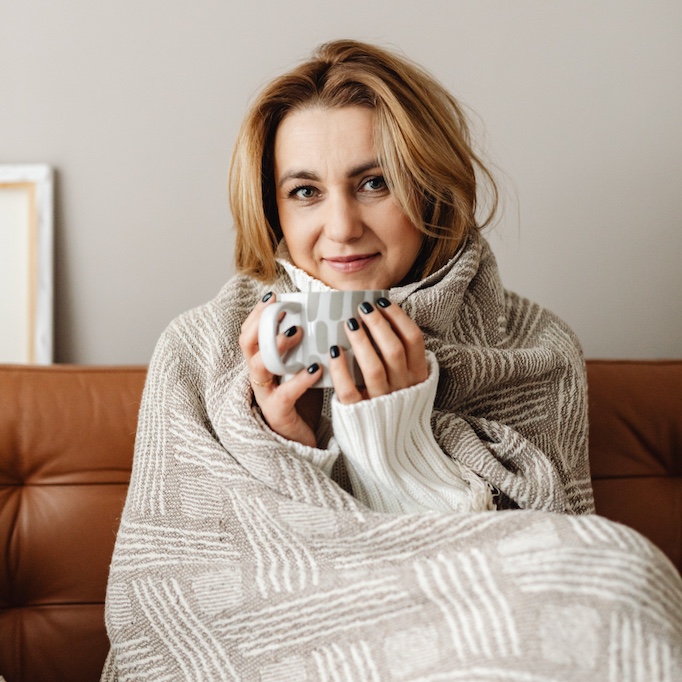 Woman wrapped in a blanket and holding a mug
